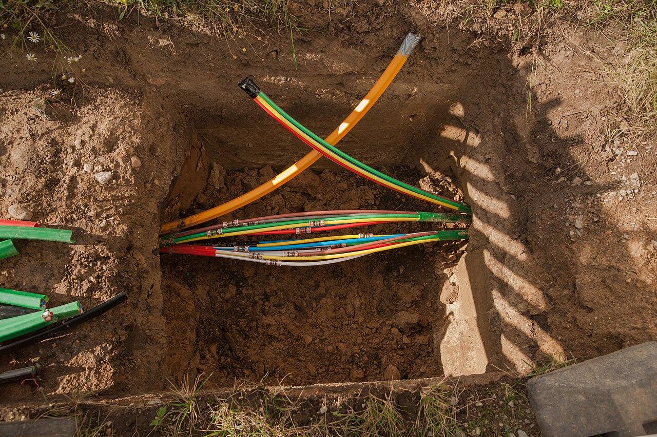 Colour-coded microducts emerging from an HDD bore into an excavated pit
